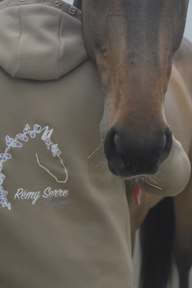 Un cheval bai pose la tête contre l'épaule de Rémy Serre